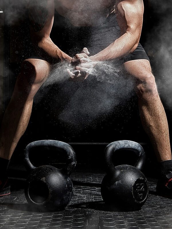 Weightlifter clapping hands and preparing for workout at a gym. Focus on dust